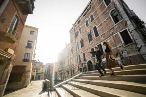 Um jovem casal atravessando caminhando por Veneza
